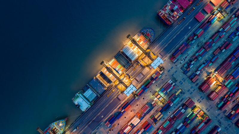 Birds-eye view of container and cargo ships at a shipyard at sunrise
