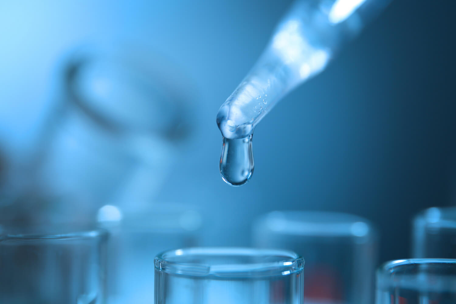 Closeup of a pipette dropping water into a test tube in a lab