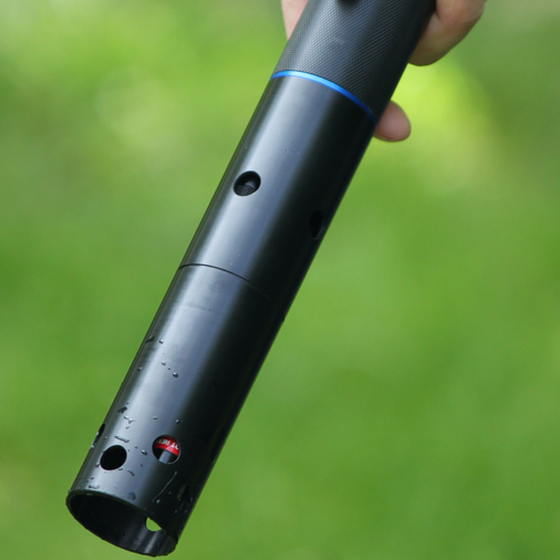 A person holds Aquaread's Aquaprobe downwards against a blurred background.