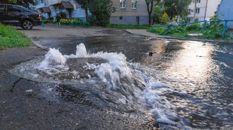 A sewer system manhole is overflowing into the street.