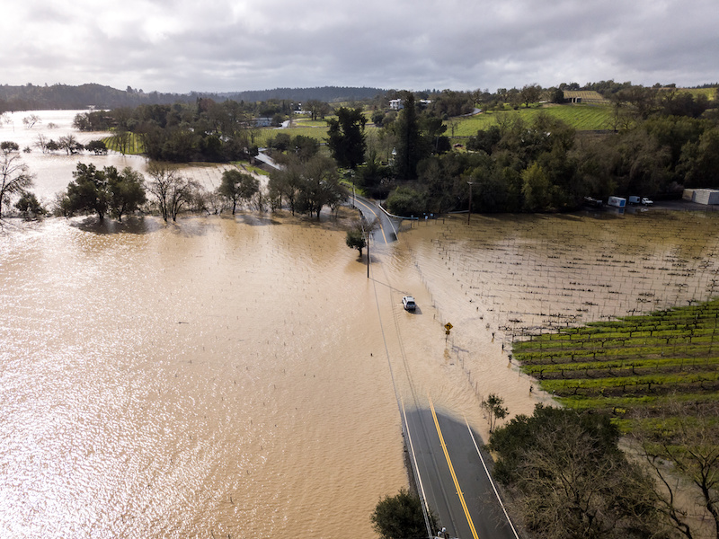 A view of a flooded river in Russia that has submerged a main road and many fields.