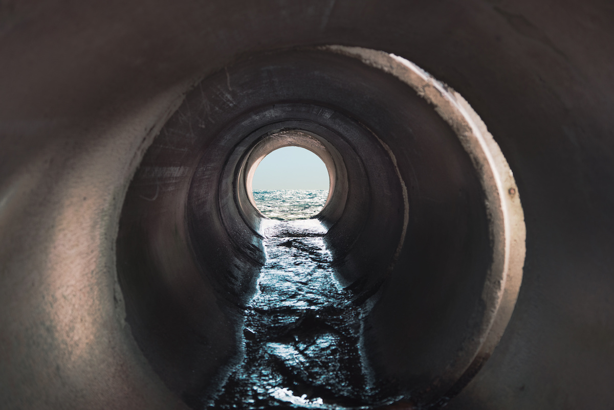 A view down a sewage pipe which flows into the sea beyond.
