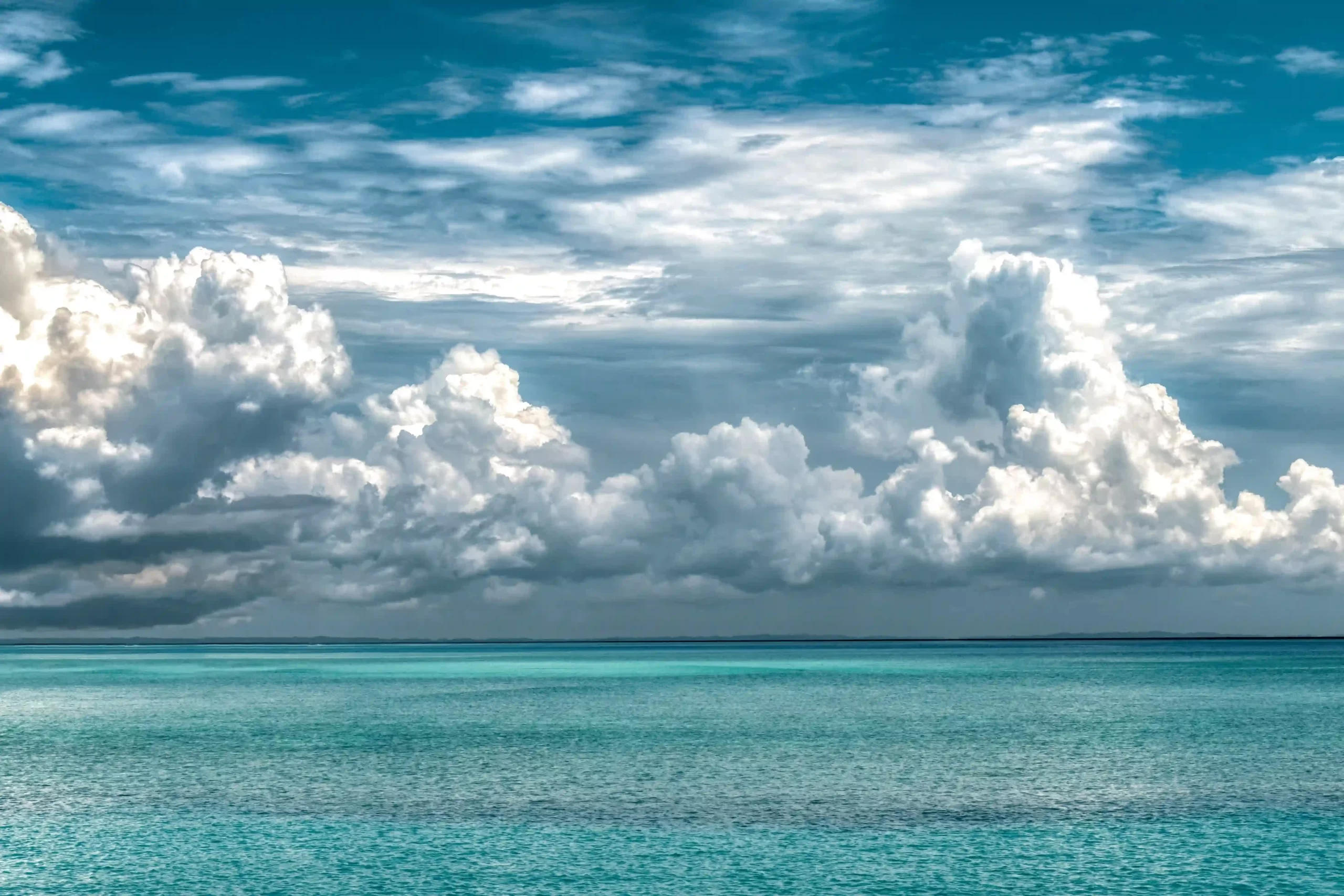 Heavy dark clouds threatening a tropical storm above a blue sea.