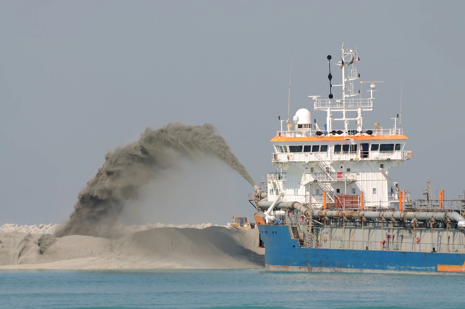 Dredge ship pushing sand to create new land.