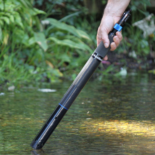 A person points the Aquasonde-2000 into a shallow stream to test the water quality.