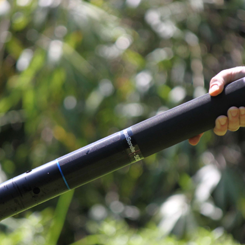 A person holds the Aquasonde-5000, a sleek black water testing meter.